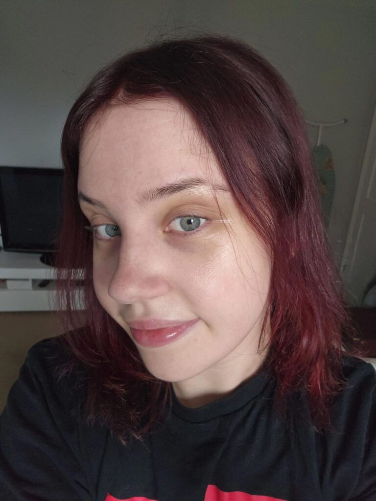 Woman with dark red hair and green eyes in a black t-shirt.